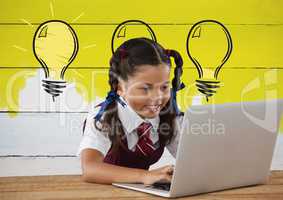 Schoolgirl on laptop with light bulbs on painted yellow wall