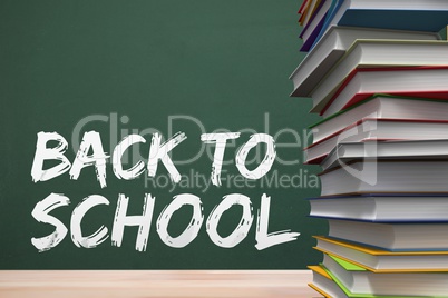 Books on the table against green blackboard with back to school text