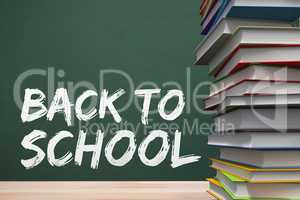 Books on the table against green blackboard with back to school text