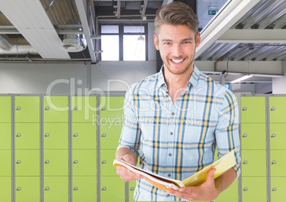 male student holding book in front of lockers