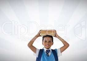 Schoolboy holding books on head with bright background