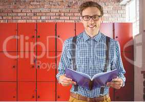 male student holding book in front of lockers