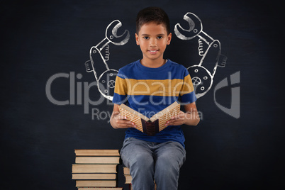 Composite image of schoolboy sitting on stack of books