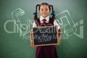Composite image of smiling schoolgirl holding writing slate