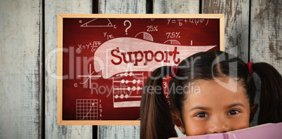 Composite image of schoolgirl covering mouth with book