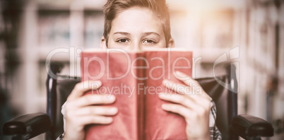 Portrait of disabled schoolboy holding book in library