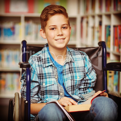 Portrait of disabled schoolboy holding book in library