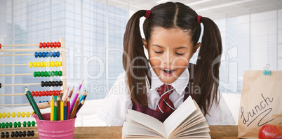 Composite image of schoolgirl reading book at desk