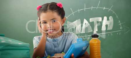Composite image of smiling girl with lunch box at table