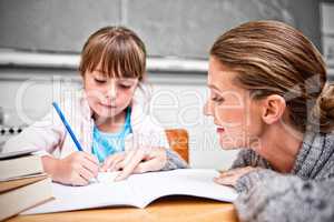 Schoolgirl writing with her teacher in classroom