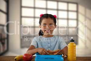 Composite image of smiling girl having sandwich at table