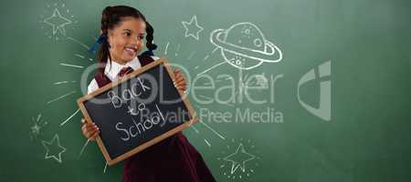Composite image of smiling schoolgirl holding writing slate