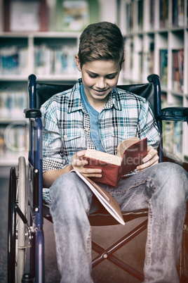 Disabled schoolboy reading book in library