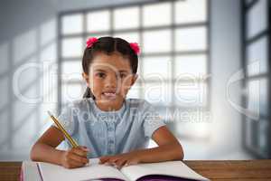 Composite image of smiling girl writing in book at desk