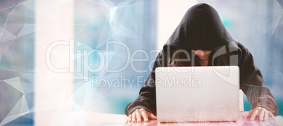 Composite image of female hacker sitting by laptop on table