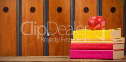 Composite image of apple with books on wooden table