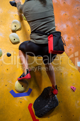 Rear view of woman practicing rock climbing