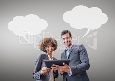 Business people with speech bubbles looking at a tablet against grey background