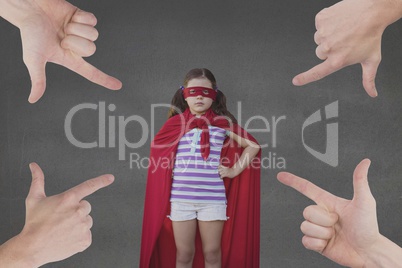 Hands pointing at girl in a super heroine custom against grey background