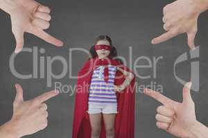 Hands pointing at girl in a super heroine custom against grey background