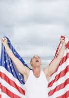 Excited man holding a USA flag in the beach