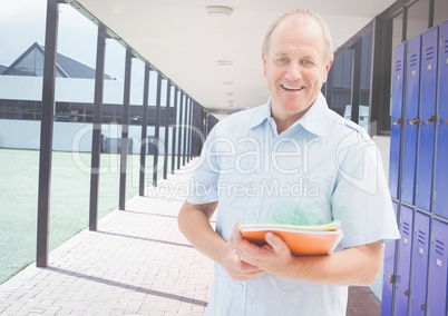 mature male student holding book in front of lockers