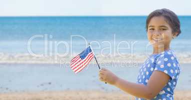 Happy girl holding a USA flag in the beach