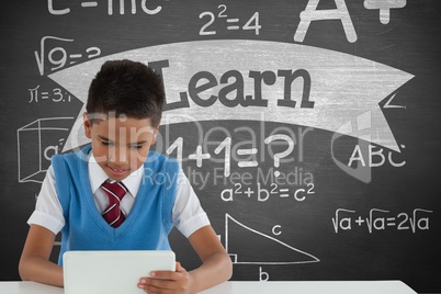 Student boy at table using a tablet against green blackboard with learn text and education and schoo