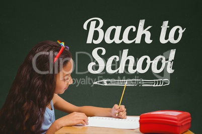 Student girl at table writing against green blackboard with back to school text