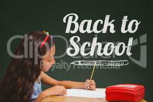 Student girl at table writing against green blackboard with back to school text