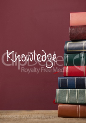 Books on the table against red blackboard with knowledge text
