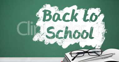 Back to school text on blackboard with glasses and book on desk