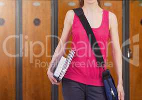 female student holding books in front of lockers