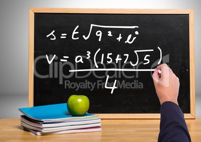 Hand writing math equations on blackboard