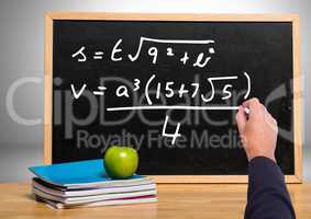 Hand writing math equations on blackboard