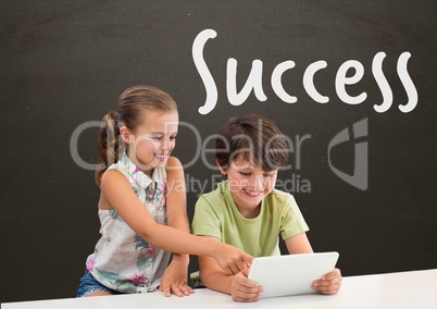 Students at table looking at a tablet against grey blackboard with success text