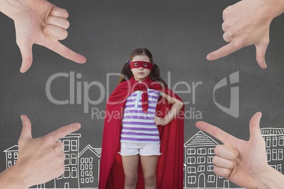 Hands pointing at girl in a super heroine custom against grey background with city illustration