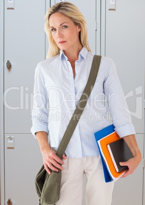 male student holding books in front of lockers