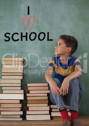 Student boy on a table thinking against green background with I love school text