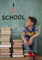 Student boy on a table thinking against green background with I love school text
