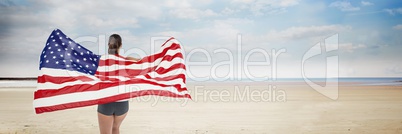 Woman holding USA flag against beach background