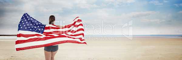 Woman holding USA flag against beach background