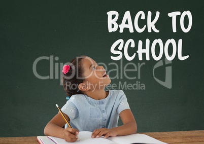 Student girl at table looking up against green blackboard with back to school text