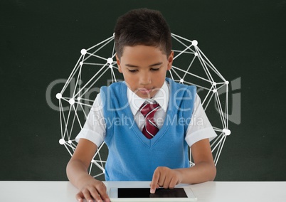 Student boy at table using a tablet against green blackboard with education graphic