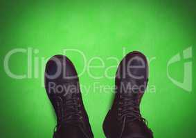Black shoes on feet with green background