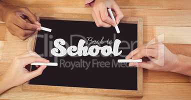 Hands writing back to school on blackboard