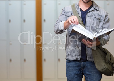 male student holding book in front of lockers