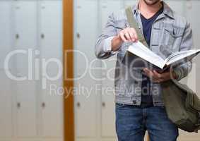 male student holding book in front of lockers