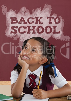 Happy student girl at table against red blackboard with back to school text