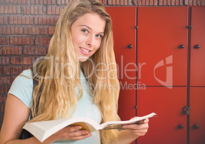 female student holding book in front of lockers